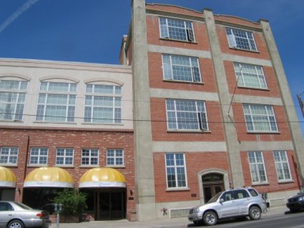 A car parked in front of a building with two windows.