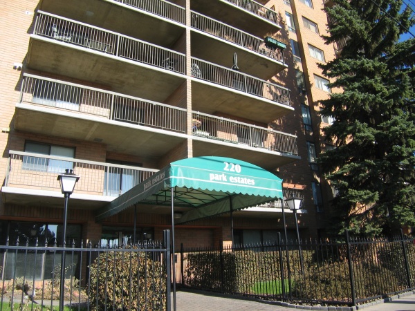 A building with a green canopy and trees in the background.